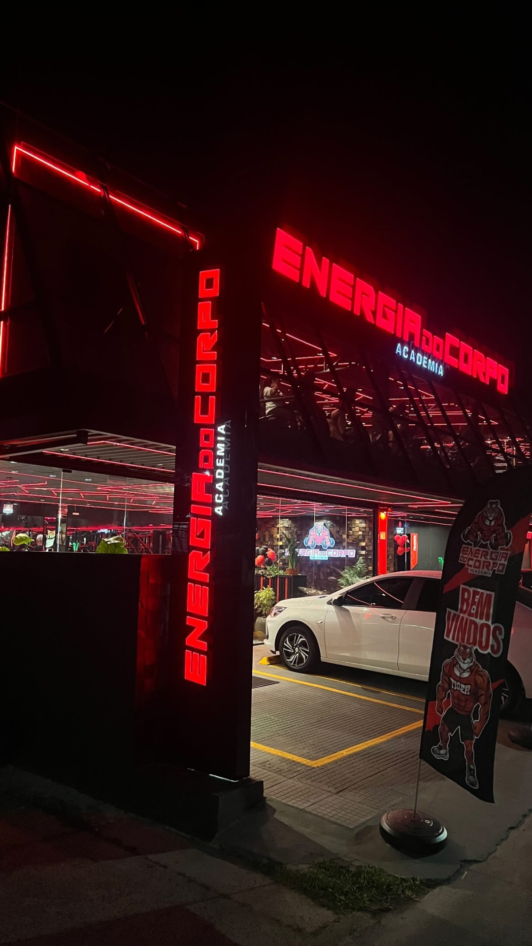 Fachada noturna da academia Energia do Corpo com letreiro luminoso vermelho