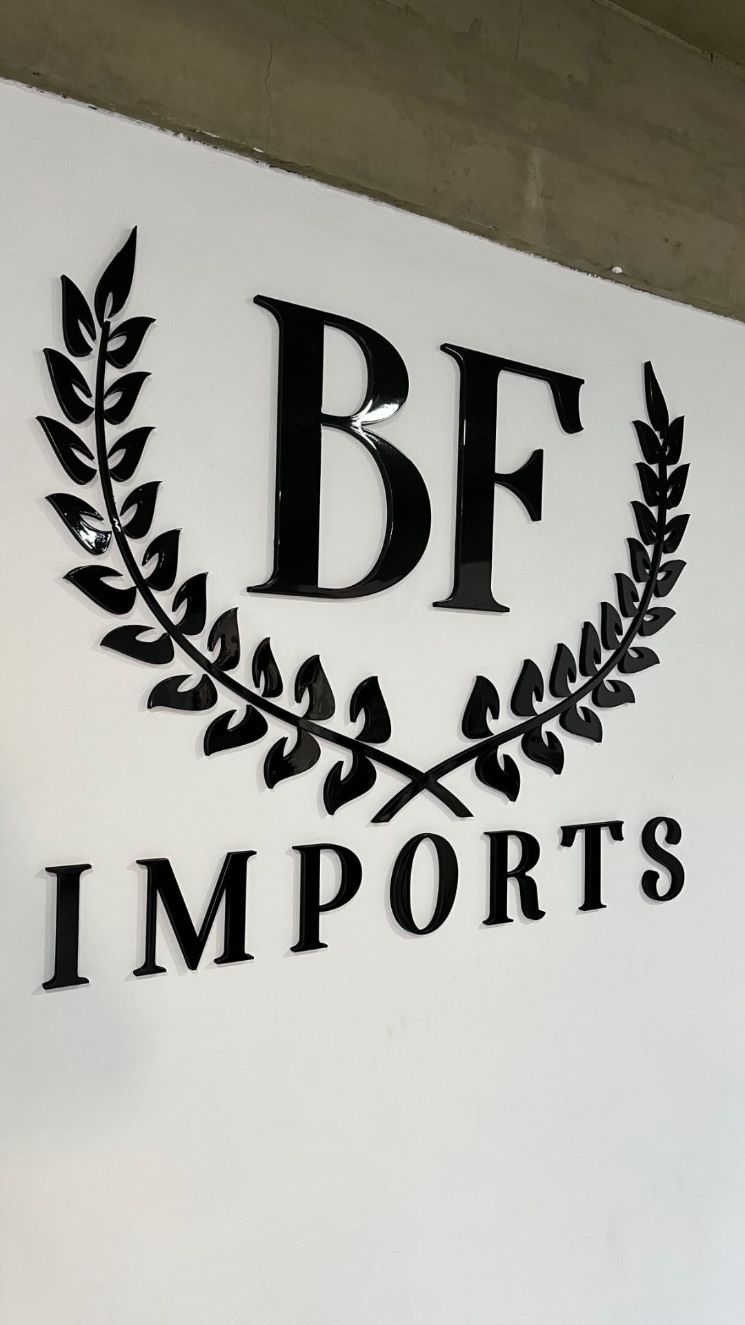 Letras caixa 3D pretas com o logo BF Imports aplicado na parede